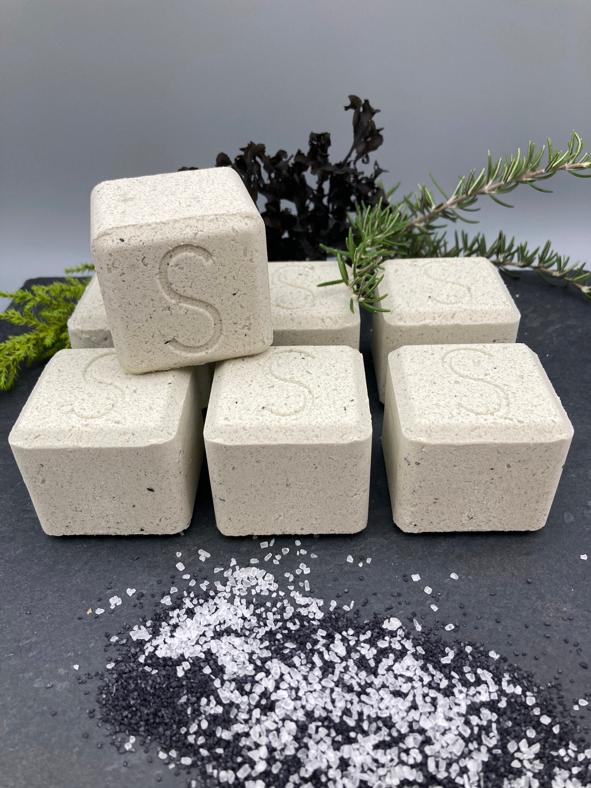 Seven Seatox Bath drops near herb sprigs and sea salt.