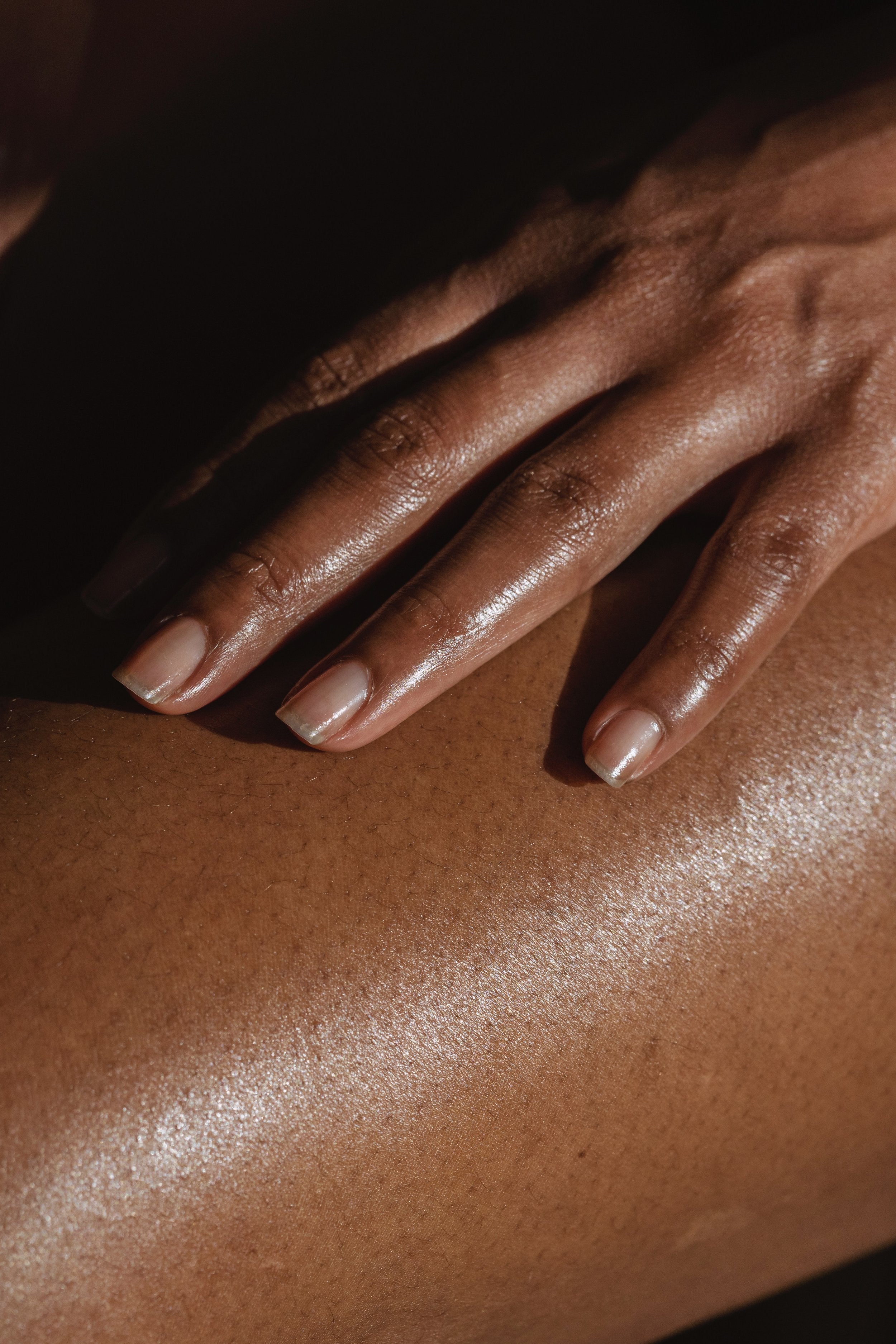 Woman's hand applying vegan body oil on her skin.